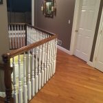 Example of hardwood floor on second floor with railing by a staircase.